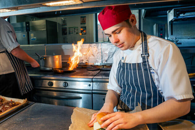 A student preparing a burget in The Wharncliffe Restaurant kitchen