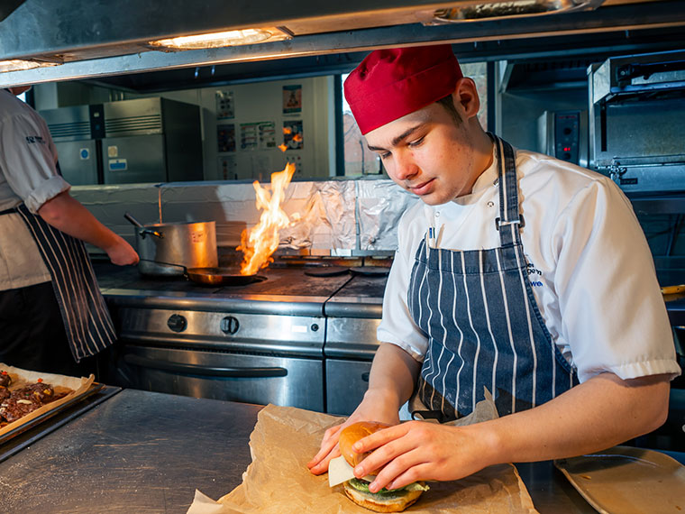 A student preparing a burget in The Wharncliffe Restaurant kitchen