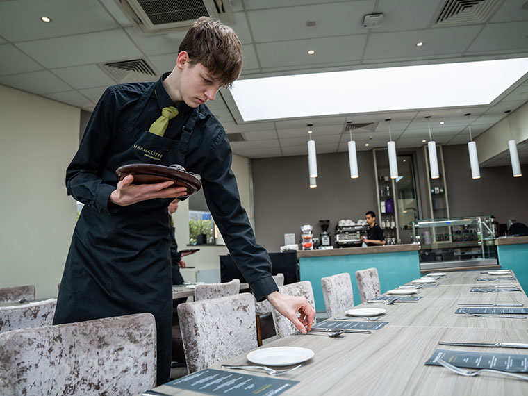 A student laying the table at The Wharncliffe Restaurant