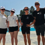 Four students stood by a swimming pool smiling at the camera