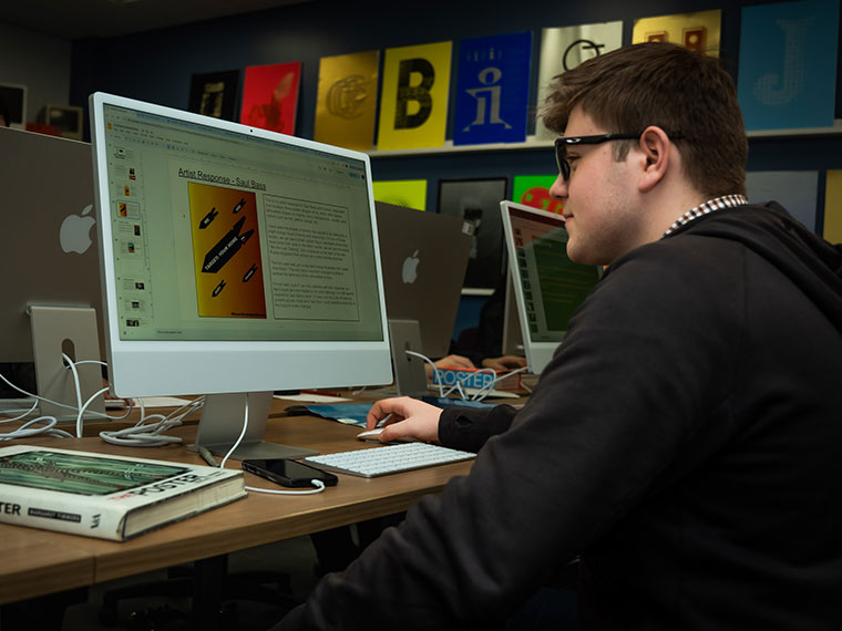 A student working on a computer in the graphics studio